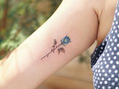 a woman's arm with a blue rose tattoo on the left side of her arm