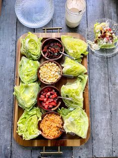 lettuce and other foods are arranged on a wooden platter with utensils