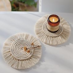 a candle sitting on top of a white table next to a round doily with a rope