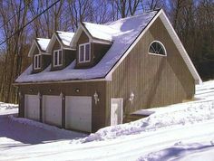 a house with three garages and snow on the ground in front of some trees