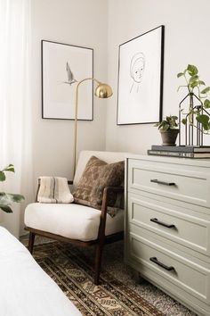 a white chair sitting next to a dresser in a room with plants on top of it