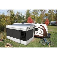 an rv is parked in the grass next to a bicycle and trees with leaves on them