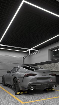 a grey sports car is parked in a parking garage with yellow lines on the floor