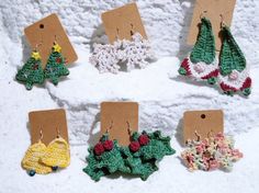 small crocheted christmas decorations are displayed on a white surface with tags attached to them