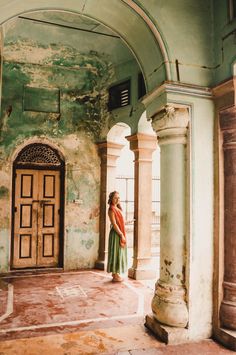 a woman is standing in an old building with columns and arches on either side of the door