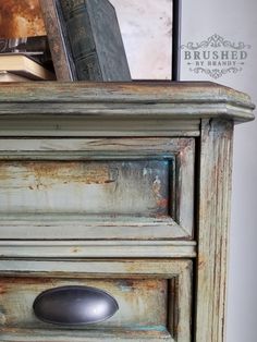 an old dresser with some books on top and a book in the drawer next to it