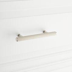 a close up of a metal handle on a white cabinet