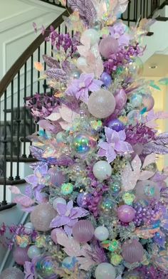 a very pretty purple christmas tree in the middle of a staircase way with lots of decorations on it