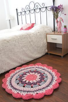 a crocheted rug is placed on the floor in front of a bed and nightstand