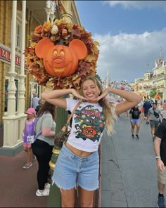 a woman standing in front of a mickey mouse head on top of a sign that says disneyland