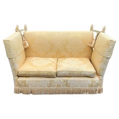 a couch with two pillows on it and fringe trimming around the armrests