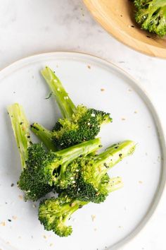 broccoli florets on a white plate next to a bowl of seasoning