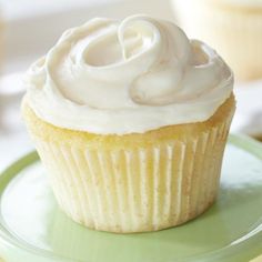 a cupcake with white frosting on a green plate