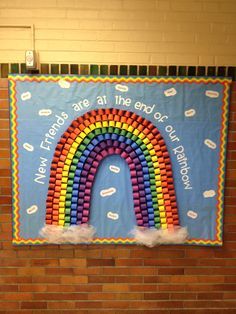 a bulletin board with a rainbow made out of legos on the side of a brick wall