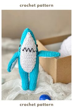 a crocheted stuffed shark sitting next to a box