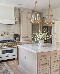 a large kitchen with an island in the middle and two pendant lights hanging from the ceiling