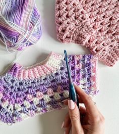 someone is crocheting together with yarn on the table next to some knitting supplies