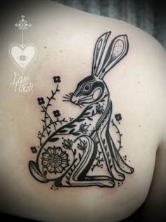 a black and white rabbit tattoo on the back of a woman's left shoulder