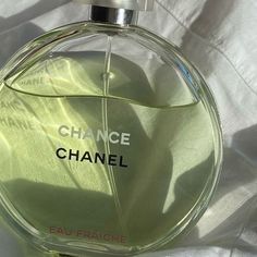 a bottle of chanel perfume sitting on top of a white sheet covered bedding