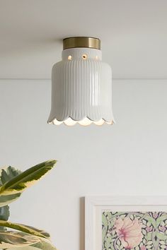 a white light hanging from the ceiling above a potted plant