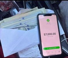 a cell phone sitting on top of a pile of cash next to a bunch of envelopes