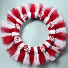 a red and white tulle wreath with candy canes on the front, sitting on a table