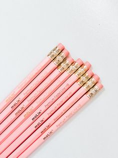 six pink pencils lined up on top of each other with gold trimmed ends