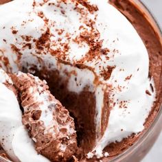 a close up of a cake in a pan with whipped cream and chocolate shavings