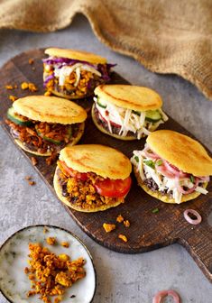 several sandwiches with meat and vegetables on a cutting board