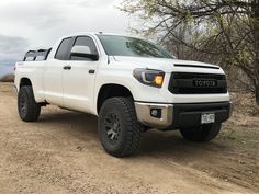 a white truck parked on top of a dirt road