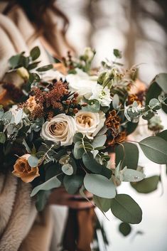 a woman holding a bouquet of flowers and greenery in her hands while wearing a fur coat