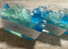 two blue and green ice cubes sitting on top of a wooden table