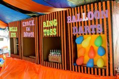 an orange and black carnival booth with balloons on it