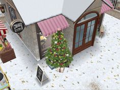 a small christmas tree is in front of a building with a pink awning on the roof