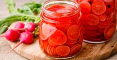 two jars filled with pickles sitting on top of a wooden cutting board next to radishes