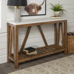 a wooden table with a lamp on top and a cow painting above it in a living room