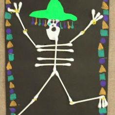 a paper skeleton with a green hat on it's head and arms, in front of a black background