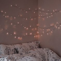 there is a bed with white sheets and lights on the wall above it in this bedroom