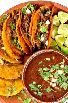 mexican food with tortillas, salsa and limes on a plate next to sliced avocado