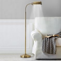 a living room with a white couch and a gold lamp on the floor next to it