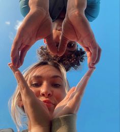 two people holding their hands up in the air with one person's head above them