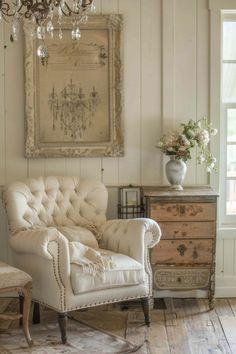 a white chair sitting on top of a wooden floor next to a dresser and chandelier