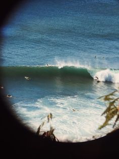 a view through a magnifying glass shows surfers in the ocean