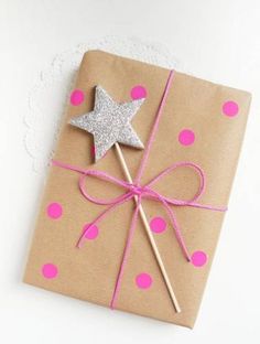 an image of a gift wrapped in brown paper with pink polka dots and a star on top