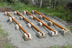 a group of benches sitting on top of a sandy beach next to grass and trees