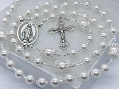 *Beautiful white European glass pearls make up the Hail Mary Beads and are paired with white  pearls crowned in a lacy silver cap  for the Our Father Beads.  Silver and crystal seed beads sprinkled throughout this rosary.  CRUCIFIXES May vary depending on availability.  Crucifixes are silver plated and made in Italy. PERSONALIZATION If you desire personalization, the name or initials will be blended in the 3rd decade of this rosary using round pewter letter beads.  Initials may also be added to the tail of the rosary. We chose these letter beads because they add a personal touch, but do not overtake the design of the rosary. *We use the strongest jewelry wire, crimp beads and wire guard available for strength and durability. *Most rosaries in our shop, measure approximately 17-19 inches lo Wedding Rosary, Rosary Gift, Pearls Wedding, 1st Communion, Crimp Beads, Silver Caps, Hail Mary, Wedding Etsy, Letter Beads