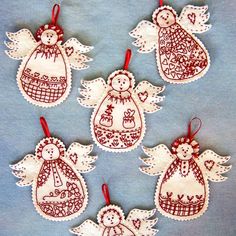 four christmas angel ornaments with red string hanging from them on a blue cloth covered surface