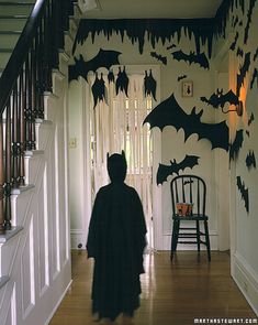 a person in a bat costume walking down a hall way with bats on the wall