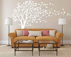 a living room filled with furniture and a white tree wall decal on the wall