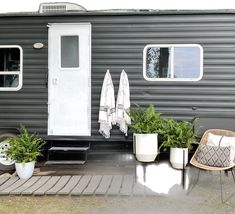 a tiny house with potted plants and towels on the porch